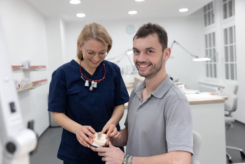 Oralchirurgin und Zahntechniker besprechen ein Zahnmodell 