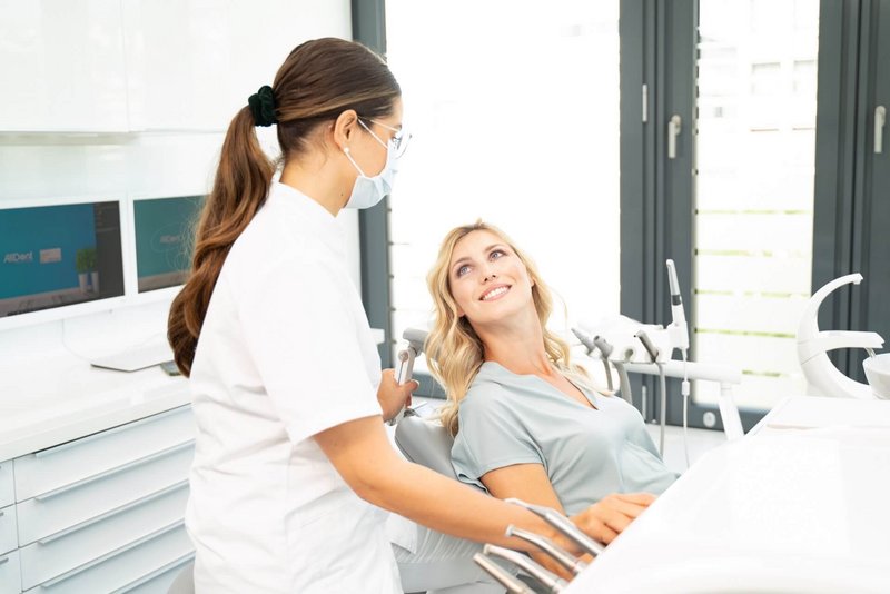 Zahnärztin sitzt neben ihrer Patientin und erklärt den Behandlungsablauf 