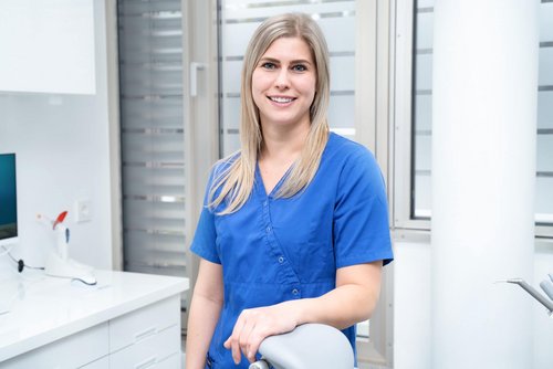 ZMP lehnt am Behandlungsstuhl in ihrem Behandlungszimmer und lächelt in die Kamera