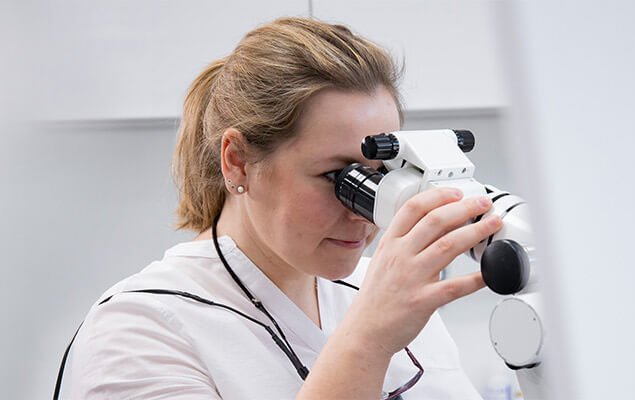Endodontologin arbeitet am Mikroskop