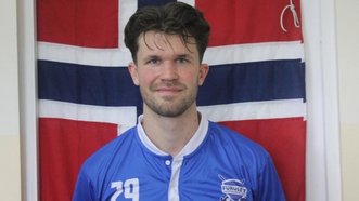 Porträt eines Hockeyspielers im blauen Trikot vor einer rot-weiß-blauen Flagge.